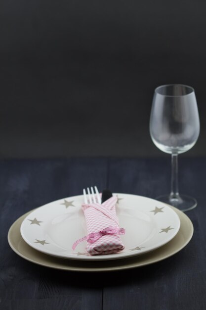 Réglage de la table d'assiettes et d'un verre à vin avec des couverts en argent enveloppés dans une serviette