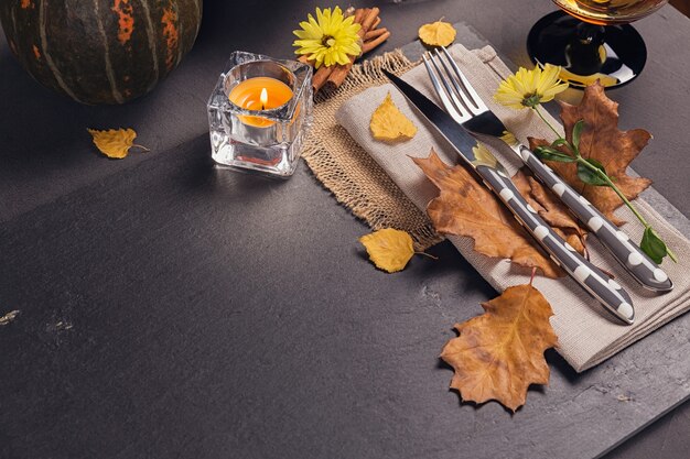 Réglage de la table avec décoration d'automne pour Thanksgiving. Feuilles sèches avec couverts et verre. Fond d'automne de Thanksgiving