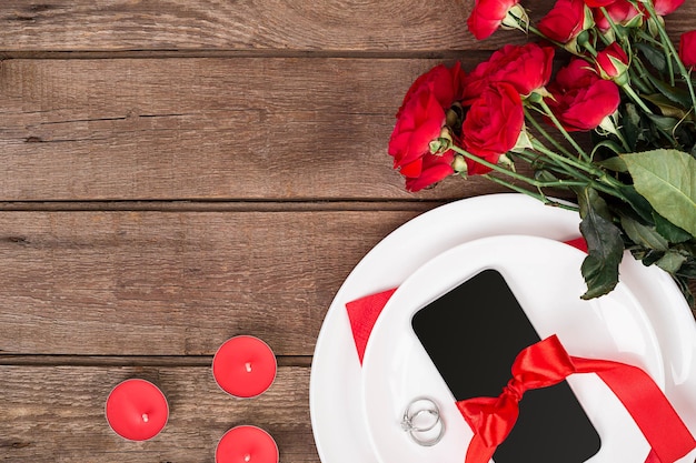 Réglage de la table du dîner de la saint-valentin avec ruban rouge roses couteau et anneau de fourchette sur fond de chêne