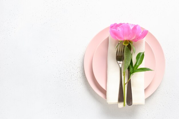 Réglage de la table de fête avec des fleurs de pivoine rose sur une table blanche vue d'en haut