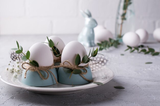 Réglage de la table de fête de Pâques avec des œufs de poule blancs dans des coquetiers, des brins de feuilles d'eucalyptus. .