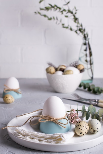 Réglage de la table de fête de Pâques avec des œufs de poule blancs dans des coquetiers, des brins de feuilles d'eucalyptus. .