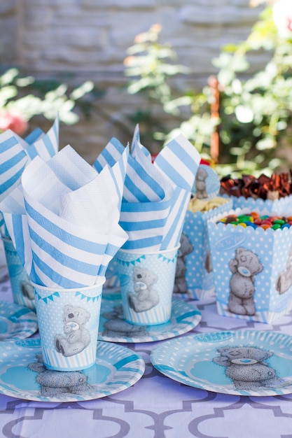 Réglage de la table de fête pour les enfants. Décoration pour la fête des enfants. Nounours à la mode. Les colis, les biscuits, les tasses, les assiettes et les serviettes sont blanc-bleu.