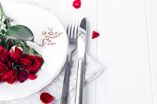 Réglage de la table de fête avec roses beiges, verres à vin, serviettes de table et couverts