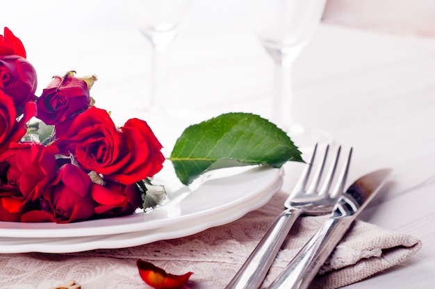 Réglage de la table de fête avec roses beiges, verres à vin, serviettes de table et couverts