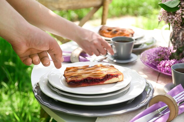 Réglage de la table avec des fleurs lilas et des gens dans le jardin de printemps