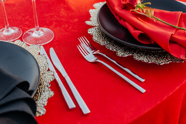 Réglage de la table d'invités pour le banquet dans des assiettes de nappe de décor de dîner élégant de style noir rouge et or