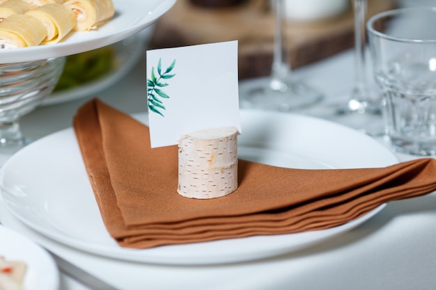 Réglage de la table de mariage avec carte d'hôte vierge sur un plat