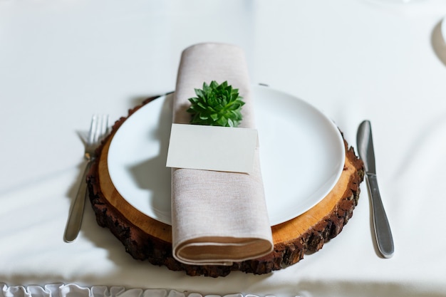 Réglage de la table de mariage avec serviette de carte d'invité vierge succulente sur plaque en bois décor rustique