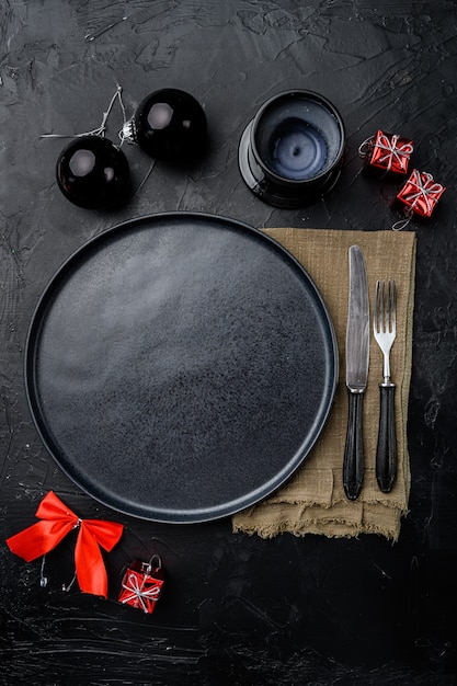 Réglage de la table de Noël avec un ensemble d'assiettes en céramique vide, vue de dessus à plat, avec espace de copie pour le texte ou la nourriture, sur fond de table en pierre noire noire