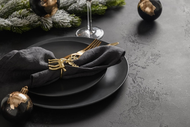 Réglage de la table de Noël avec plaque noire et décorations dorées sur fond noir