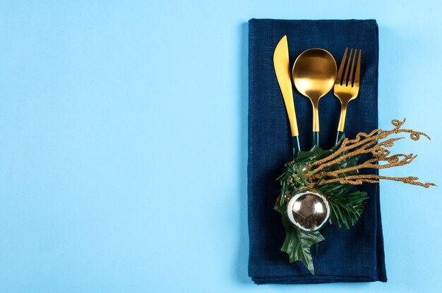 Réglage de la table de Noël avec vaisselle moderne et décorations sur fond bleu. Vue de dessus. Couvert de nouvel an. Vaisselle de Noël. Couvert de Noël. Couverts de dîner de Noël avec décor.