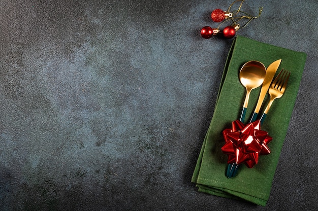 Réglage de la table de Noël avec vaisselle moderne et décorations sur fond sombre. Vue de dessus. Couvert de nouvel an. Vaisselle de Noël avec décorations. Couvert de Noël.