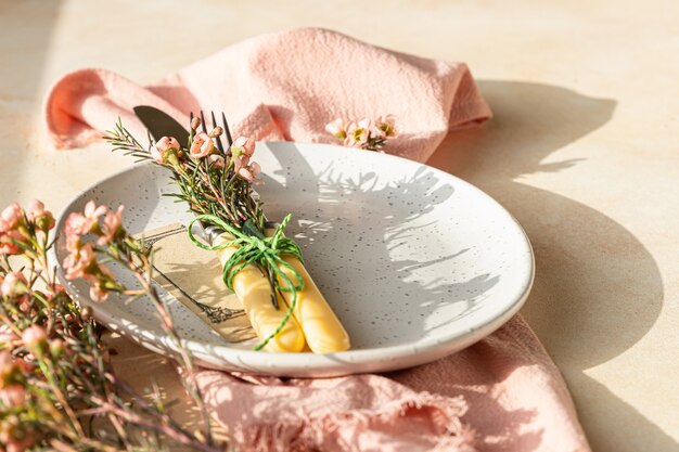 Réglage de la table de Pâques avec assiette, couverts et fleurs roses