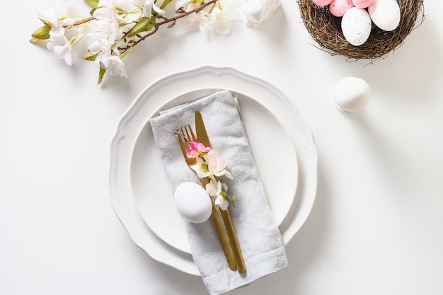 Réglage de la table de Pâques avec des fleurs de pomme en fleurs sur un tableau blanc.
