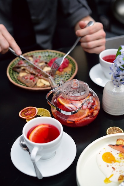 Réglage de la table de petit déjeuner avec des crêpes, du thé. Couple mange