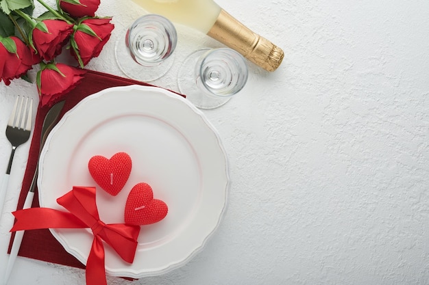 Réglage de la table romantique de la Saint-Valentin Vide ou gros plan d'une fourchette de couteau de plaque noire et de coeurs de soie décoratifs sur fond blanc Concept de vacances Espace de copie pour les inscriptions