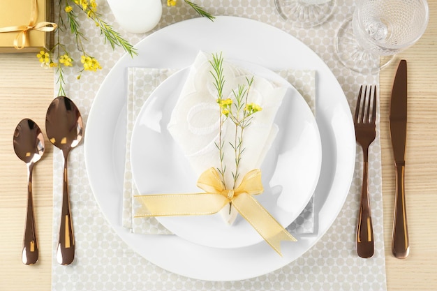 Réglage de la table avec serviette de couleur claire et décor floral sur une surface en bois