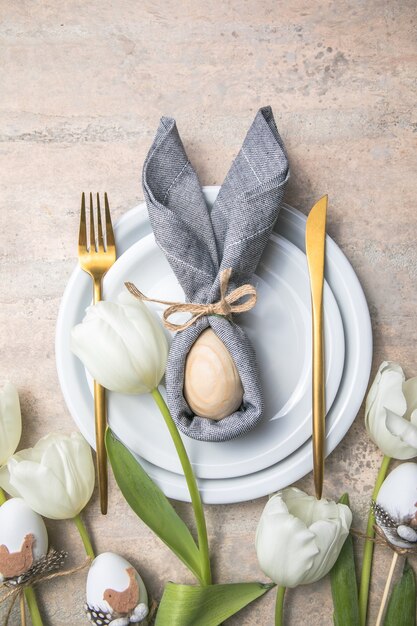 Réglage de la table de vacances de Pâques avec lapin d'oeuf sur plaque blanche et fleurs de tulipes.