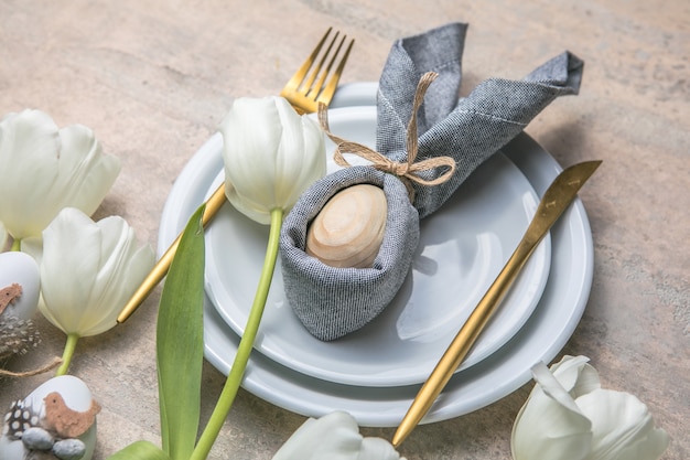 Réglage de la table de vacances de Pâques avec lapin d'oeuf sur plaque blanche et fleurs de tulipes.