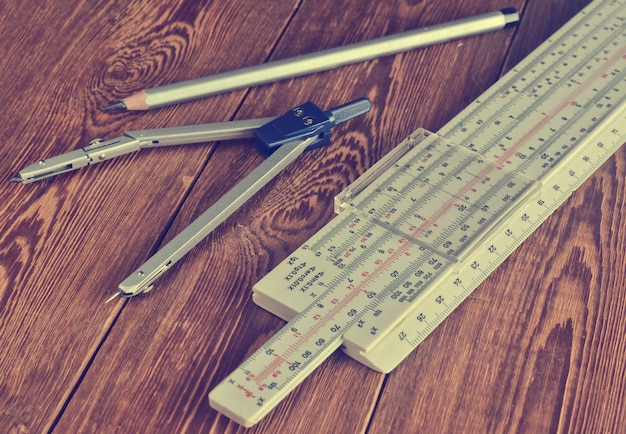Photo règle logarithmique, compas, crayon sur une table en bois.