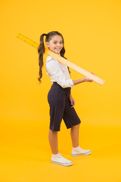 La règle rend le dessin plus beau Petit enfant tenant un instrument de dessin sur fond jaune Petite fille utilisant une règle pour tracer des lignes droites Avoir des leçons de géométrie ou de dessin technique