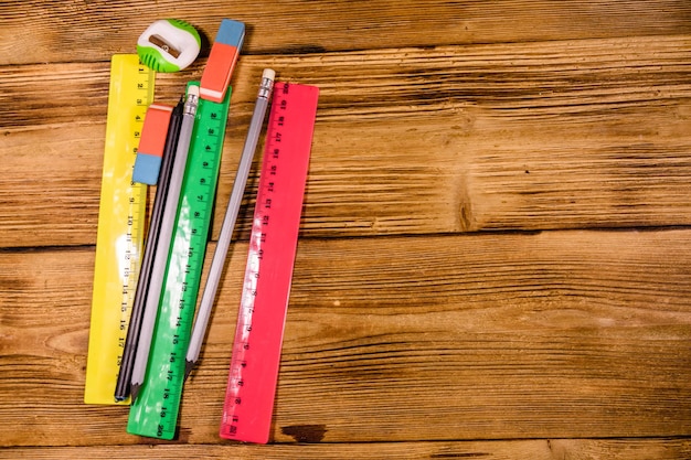 Règles, crayons et gommes sur une table en bois. Vue de dessus