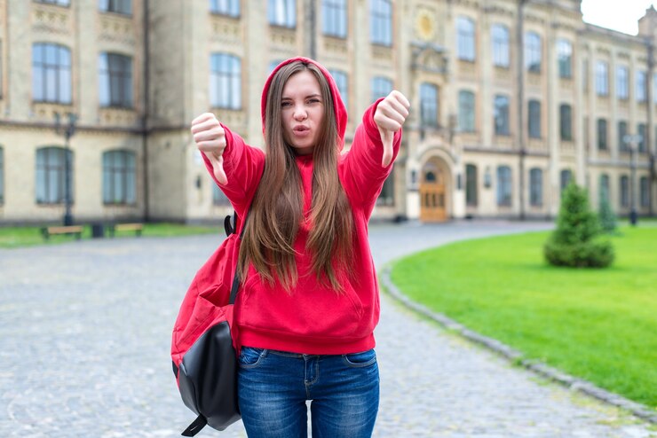 Les règles enfreignent le concept. Photo de frappant exprimant son indignation adolescente rebelle hipster en sweat à capuche montrant le symbole des doigts vers le bas