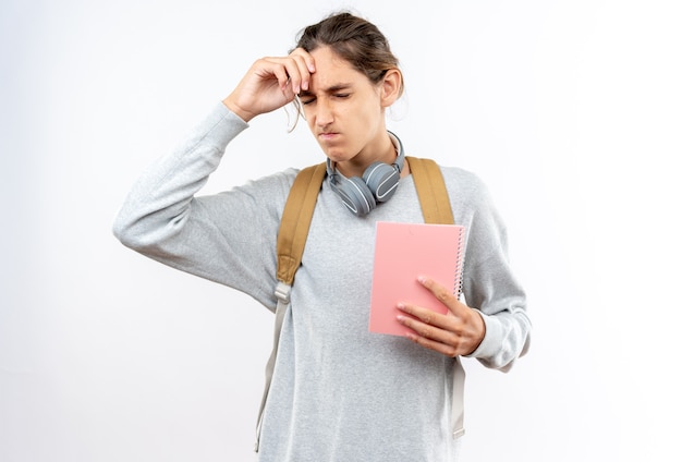 Regretté Avec Les Yeux Fermés Jeune étudiant Portant Un Sac à Dos Avec Des écouteurs Sur Le Cou Tenant Un Ordinateur Portable Mettant La Main Sur Le Front