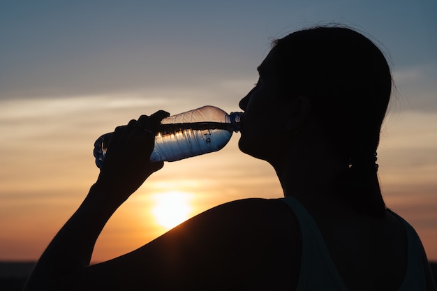 Photo réhydratez votre corps. femme sportive eau potable en plein air par une journée ensoleillée.