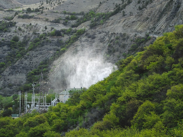 Photo rejet d'eau dans les centrales hydroélectriques. centrale hydroélectrique dans les montagnes couvertes d'une forêt verdoyante.