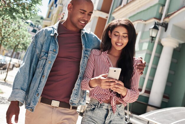 Relation romantique jeune couple diversifié marchant dans la rue de la ville étreignant une femme parcourant