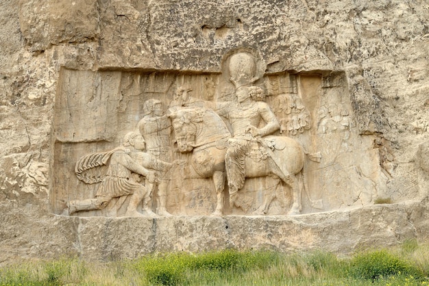 Photo un relief en pierre d'un homme et d'une femme avec une épée et un homme sur un cheval