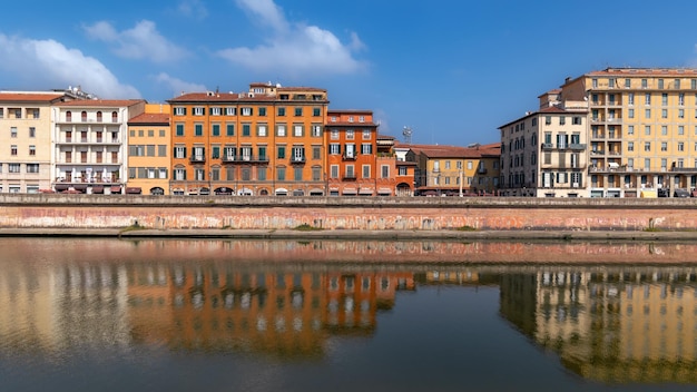 Le remblai de l'Arno avec les bâtiments résidentiels de la vieille ville se reflètent dans l'eau le jour de Pise, en Italie