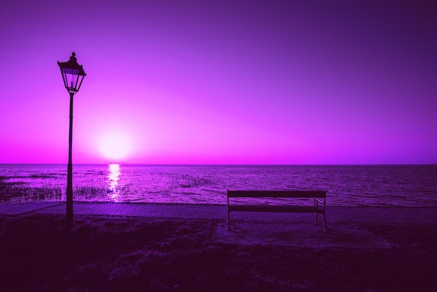 Remblai du lac avec lampe de rue et banc le soir avec ciel violet spectaculaire Coucher de soleil sur le lac Balaton Hongrie