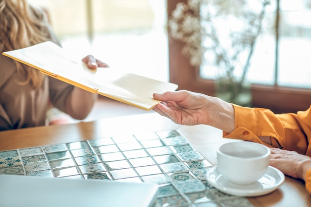 Remettre. Gros plan d'une main féminine passant les papiers au client