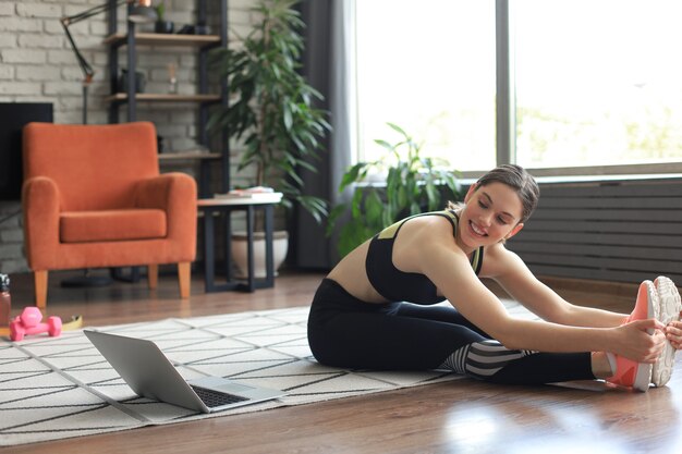 Remise en forme belle femme mince faisant des exercices d'étirement de remise en forme à la maison dans le salon. Restez à la maison activités. Sport, mode de vie sain.