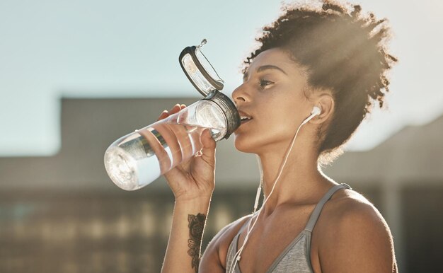 Photo remise en forme du coureur et femme buvant de l'eau avec un podcast audio en ligne pour l'entraînement ou l'entraînement en ville