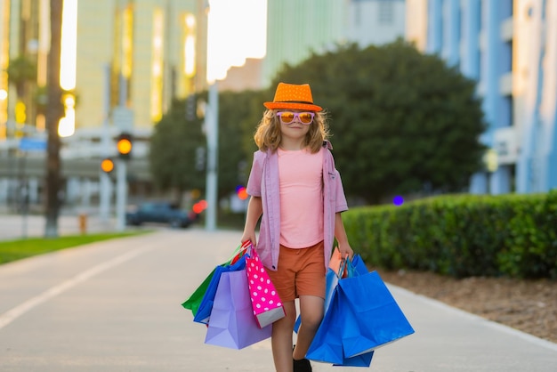 Remises et ventes happy kid boy with shopping bags petit enfant sur les tendances d'achat et les marques summ