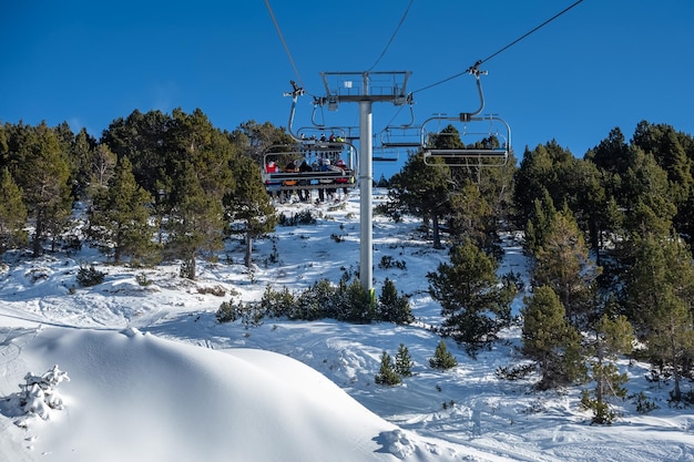 Remontées mécaniques de la station de ski avec des skieurs assis sur des chaises pour grimper haut dans les montagnes Andorre