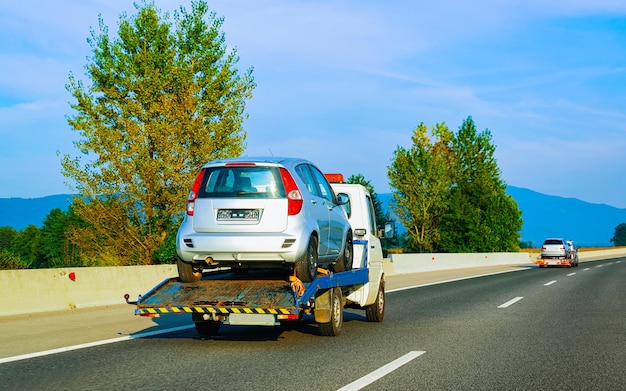 Remorque de dépanneuse basse avec voiture en route. Véhicule automatique avec transporteur Carrier sur l'allée. Logistique de transport européenne au transport de travail de transport. Transport sur autoroute.