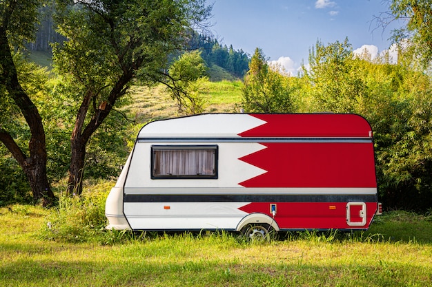 Une remorque de voiture, une autocaravane, peinte dans le drapeau national de Bahreïn est garée dans une montagne.