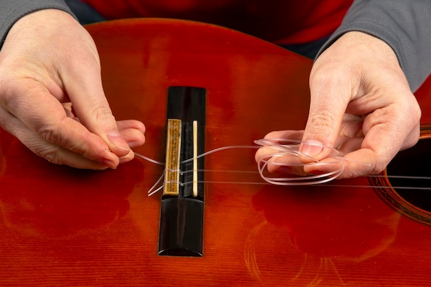 Remplacement et insertion de cordes nylon dans une guitare classique. leçon pour un musicien