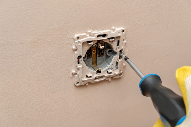 Remplacement, installation d'une prise électrique, prise de courant avec les mains dans des gants de protection en caoutchouc