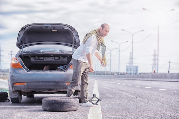 Remplacement de la roue d'une voiture sur la route Un homme faisant des travaux de pneus sur la touche