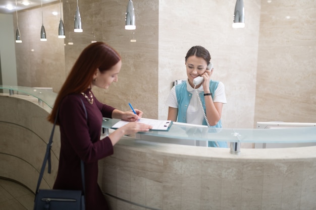 Remplir le formulaire. Belle femme rousse remplissant le formulaire pour dentiste avant examen