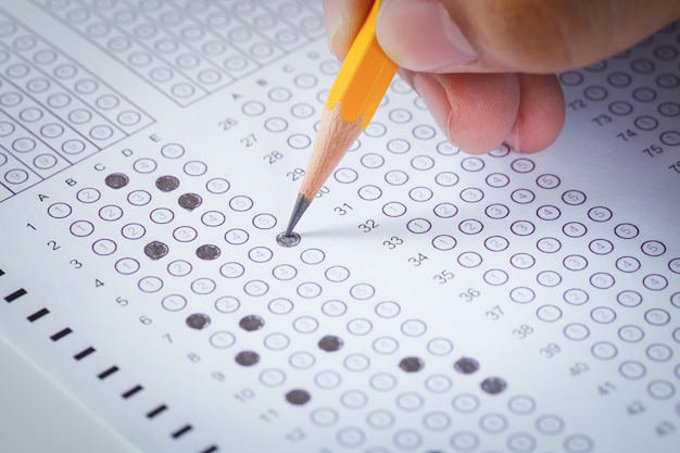 Photo remplir à la main une feuille d'ordinateur en papier carbone examen et un crayon