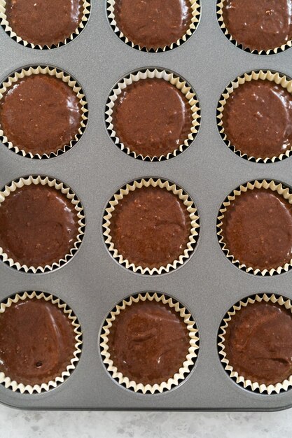 Remplir des moules à cupcakes en aluminium avec une pâte à cupcakes au chocolat pour cuire des cupcakes s'mores