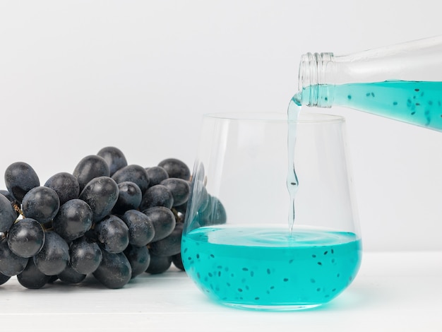 Remplir un verre en verre avec un cocktail exotique sur un raisin bleu. Une boisson rafraîchissante exotique.