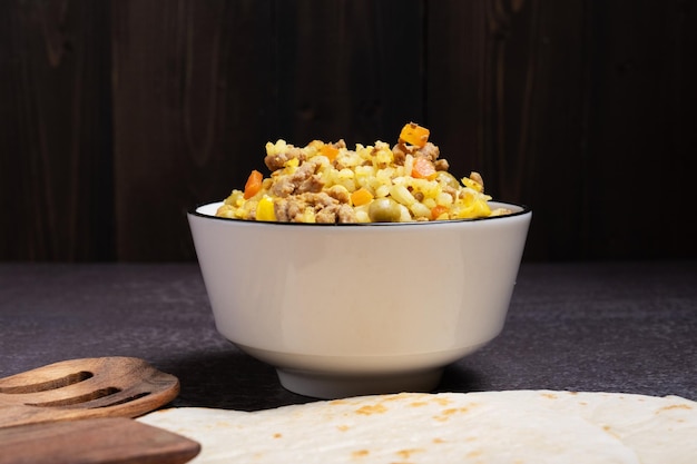 Remplissage de viande de maïs de riz pour la cuisson des tacos mexicains dans un bol blanc